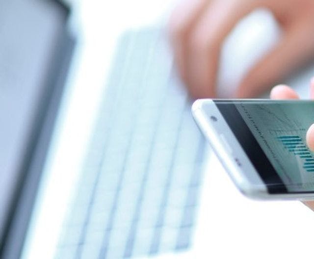 Image of a mobile phone screen and a laptop screen both showing graphs