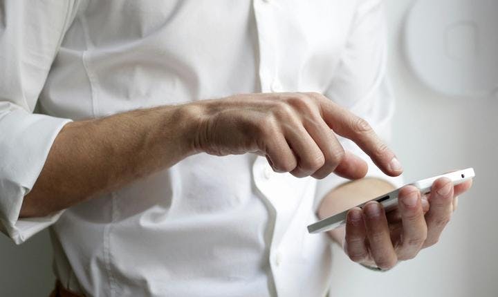 Image of a man in a white shirt touching a phone screen